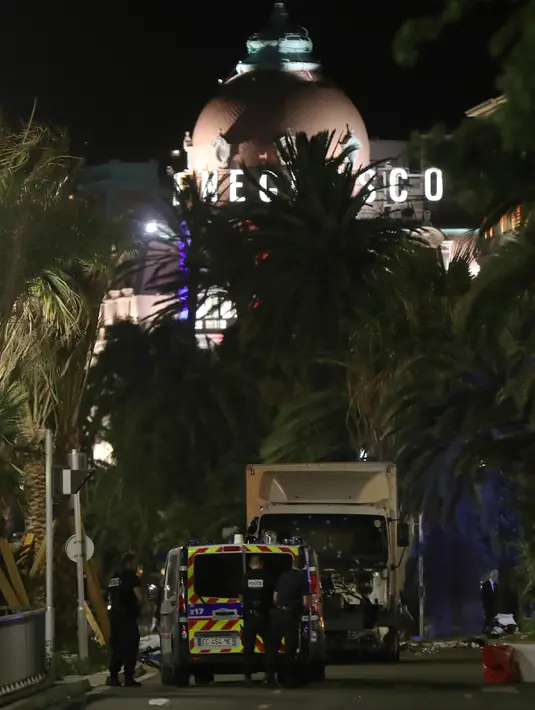Petugas kepolisian berdiri di dekat  sebuah truk yang menabrak kerumunan orang di Nice, Prancis, Kamis (14/7). Truk itu melaju cepat dengan target kerumunan massa yang menyaksikan pesta kembang api dalam perayaan Bastile Day. (VALERY HACHE/AFP)
