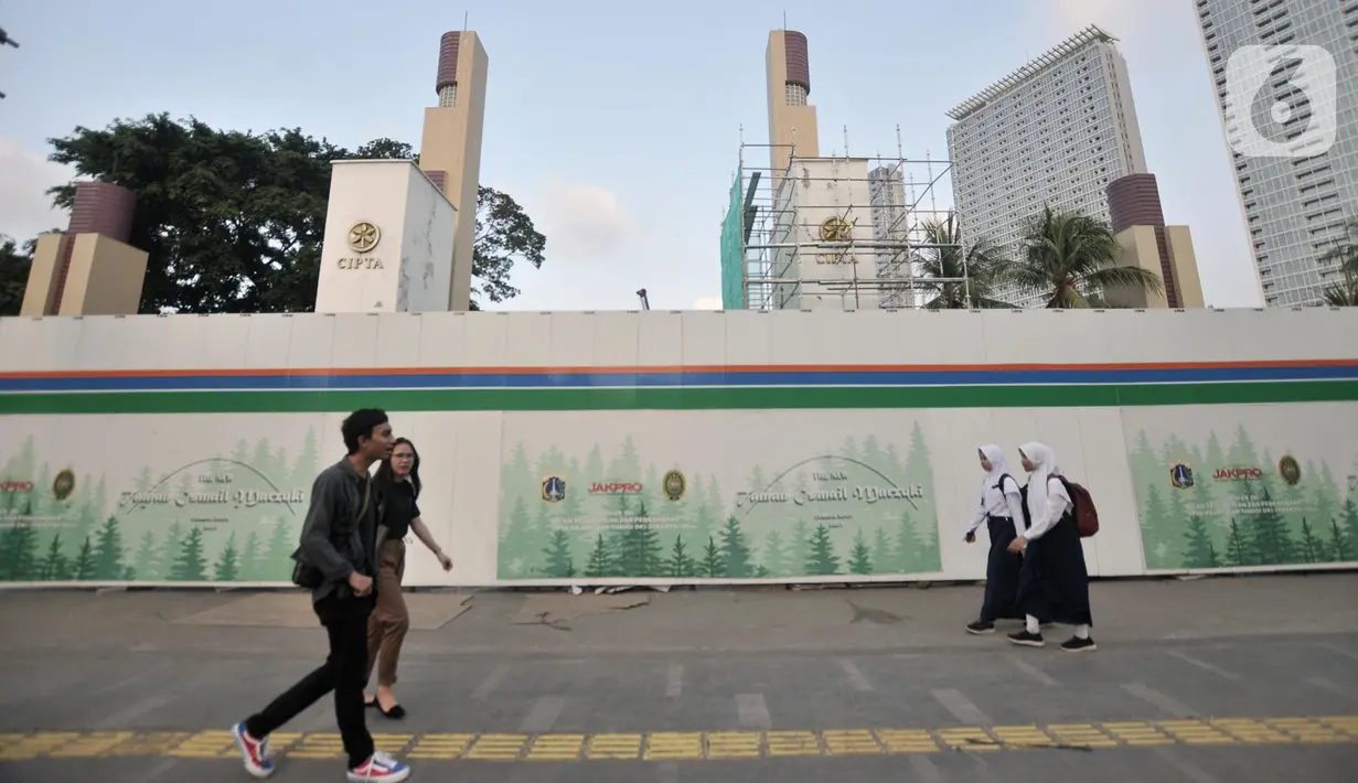 Pejalan kaki melintas di depan proyek revitalisasi Taman Ismail Marzuki (TIM), Jakarta, Selasa (26/11/2019). Pembangunan hotel berbintang di proyek revitalisasi TIM menuai penolakan dari seniman karena dinilai menjadi area komersial serta menggangu ruang berekspresi. (merdeka.com/Iqbal Nugroho)