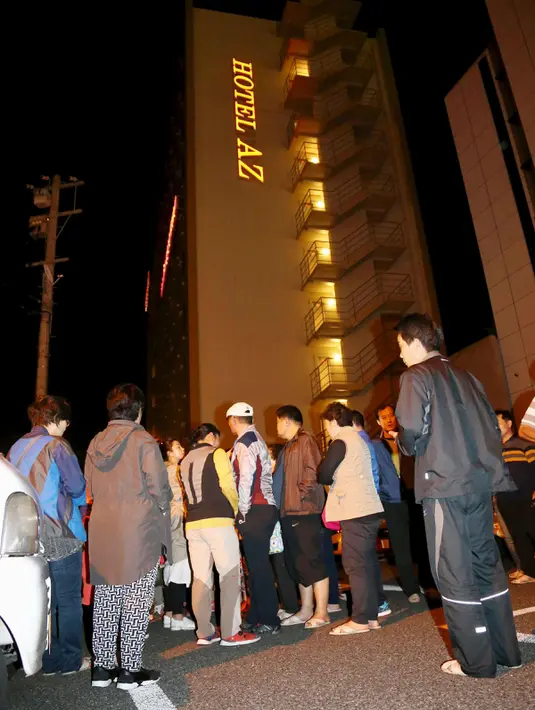 Sejumlah orang berhamburan ke jalan di depan sebuah hotel setelah gempa bumi mennguncang Kumamoto, Jepang selatan, Kamis (14/4). Gempa 6,4 SR itu juga mengakibatkan lebih dari 20 bangunan rumah hancur dan kebakaran di Prefektur Kumamoto. (REUTERS/Kyodo)