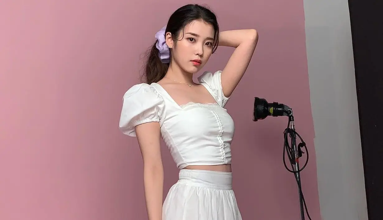 IU di sini yang tampil mengenakan set top dan skirt bernuansa putih. Top yang dikenakannya memiliki detail serut dan lengan balon, sedangkan skirtnya dihiasi sulaman bunga untuk menambahkan kesan feminin. Foto: Instagram @dlwlrma.