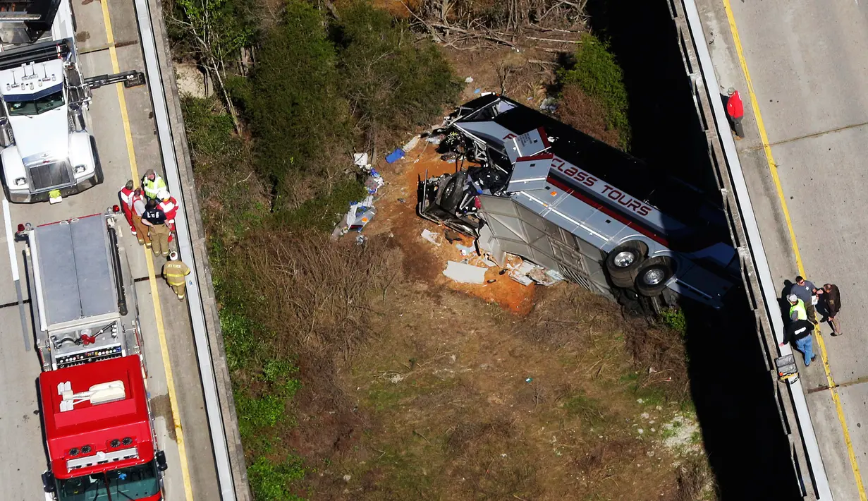 Sebuah bus carteran jatuh setelah menabrak pembatas di Loxley, Alabama (13/3). Bus tersebut membawa anggota band SMA di Texas pulang dari Disney World. (AP Photo / Dan Anderson)
