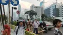 Warga menunggu angkutan umum di tepi Jalan Jenderal Sudirman, Jakarta, Senin (8/7/2019). Tidak adanya halte tersebut mengurangi kenyamanan serta mengganggu arus lalu lintas. (Liputan6.com/Immanuel Antonius)