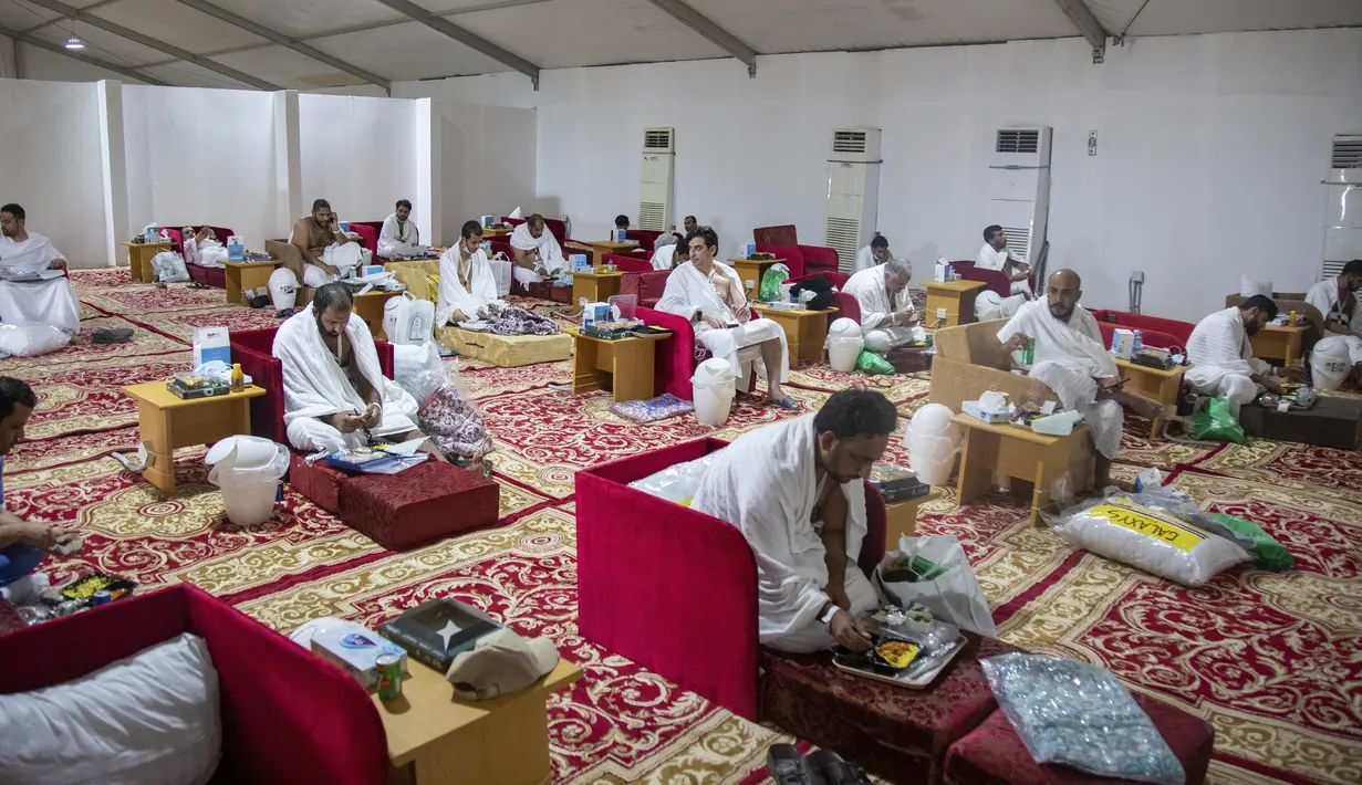 Jemaah makan dalam kamp saat melaksanakan rangkaian ibadah haji di Kota Suci Makkah, Arab Saudi, Kamis (30/7/2020). Hanya sekitar seribu jemaah yang diizinkan untuk melakukan ibadah haji tahun ini karena pandemi COVID-19. (Saudi Ministry of Media via AP)