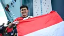 Atlet panjat tebing Indonesia, Veddriq Leonardo membentangkan bendera Merah Putih saat merayakan kemenangan pada babak final cabang olahraga pajat tebing nomor speed Olimpiade Paris 2024 di Le Bourget Sport Climbing Venue, Paris, Prancis, Kamis (08/08/2024). (AFP/Jonathan Nackstrand)