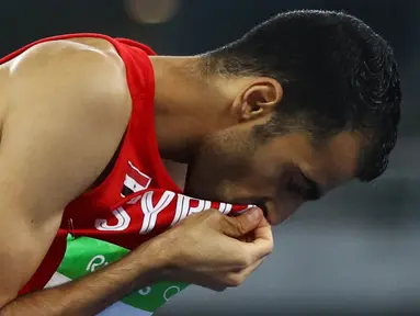 Atlet lompat tinggi Suriah, Majd Eddin Ghazal, mencium bendera negaranya usai tampil pada Olimpiade 2016 di Rio de Janeiro, Brasil, Sabtu (20/8/2016). Konflik dalam negeri tak menyurutkan semangat para atlet dari Suriah. (Reuters/Kai Pfaffenbach)