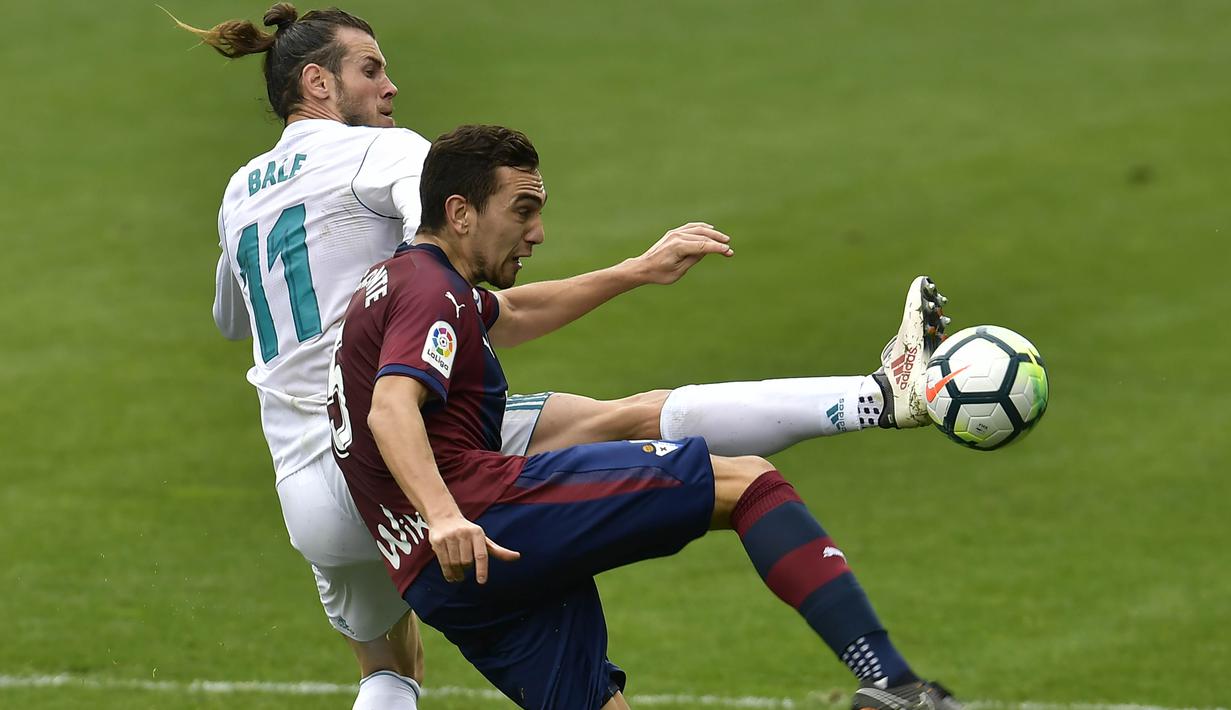 Striker Real Madrid, Gareth Bale, berebut bola dengan gelandang Eibar, Gonzalo Escalante, pada laga La Liga di Stadion Ipurua, Sabtu (10/3/2018). Eibar takluk 1-2 dari Real Madrid. (AP/Alvaro Barrientos)