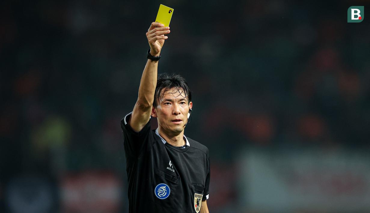 Wasit asal Jepang, Futoshi Nakamura, memberikan kartu kuning kepada salah satu pemain saat memimpin pertandingan pekan ke-23 BRI Liga 1 2023/2024 antara Persija Jakarta melawan PSS Sleman yang berlangsung di Stadion Patriot Chandra Bhaga, Bekasi, Sabtu (16/12/2023). Sepanjang pertandingan, Futoshi Nakamura mengeluarkan empat kartu kuning untuk Persija dan dua kartu kuning untuk PSS. (Bola.com/Bagaskara Lazuardi)