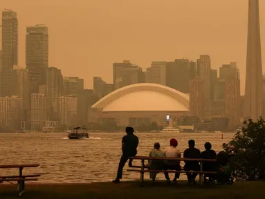 Warga memandang cakrawala pusat kota Toronto dari Kepulauan Toronto saat kabut asap akibat kebakaran hutan di Ontario Utara menyelimuti kota dan menurunkan kualitas udara, Toronto, Ontario, Kanada, Kamis, 15 Juli 2026. (AFP/ Cole Burston)