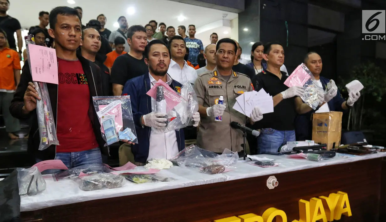 Kabid Humas Polda Metro Jaya Kombes Pol Argo Yuwono (tengah) menunjukkan barang bukti kasus kerusuhan Aksi 22 Mei saat rilis di Polda Metro Jaya, Jakarta (22/5/2019). Polisi mengamankan barang bukti di antaranya bendera hitam, bom molotov, dan mata uang asing. (Liputan6.com/JohanTallo)