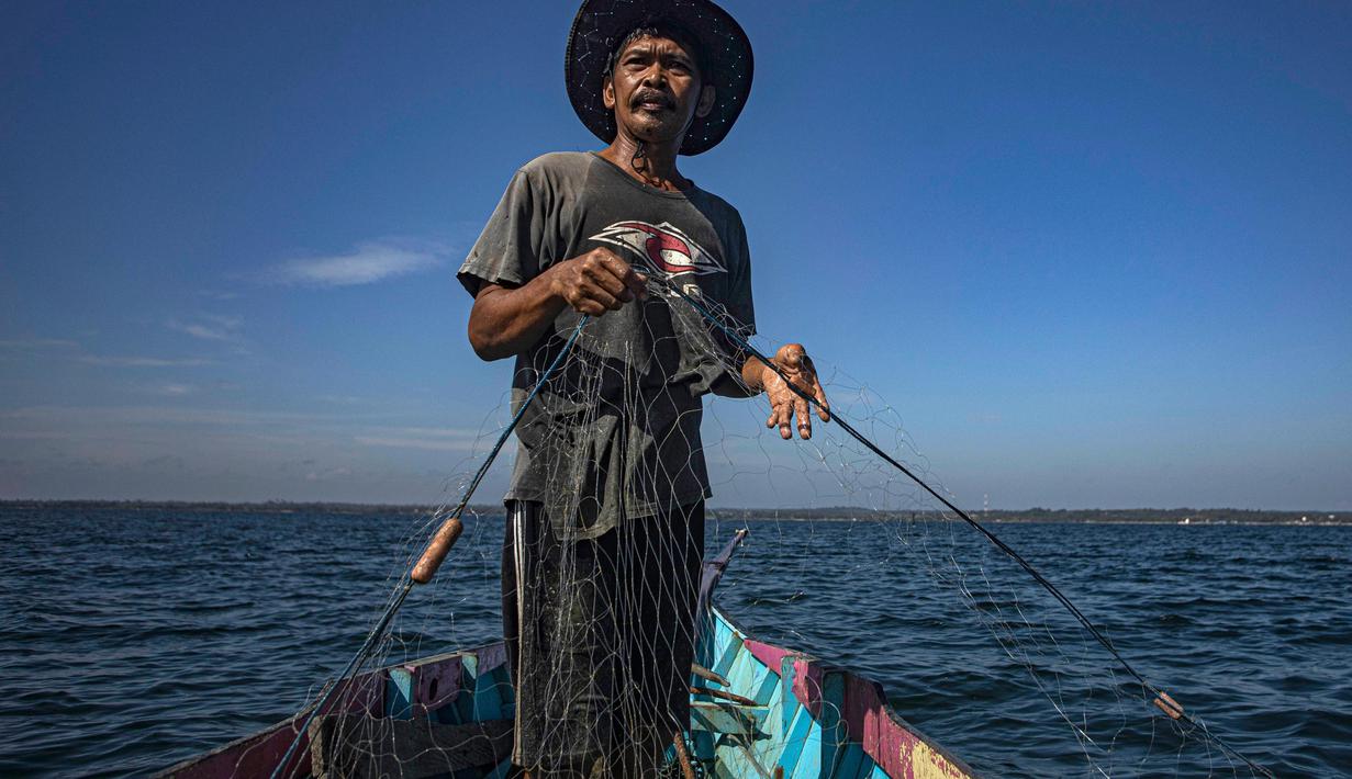 Erwin, seorang nelayan, menggunakan jaring untuk menangkap ikan di perairan Tanah Kuning, dekat lokasi pengembangan Kalimantan Industrial Park Indonesia, di Kalimantan Utara, Indonesia pada hari Kamis, 24 Agustus 2023. (AP Photo/Yusuf Wahil)