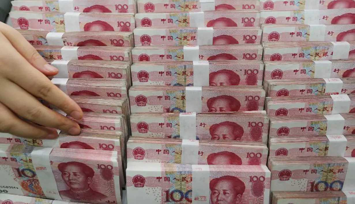 Petugas teller menghitung lembaran 100 yuan di sebuah bank di Lianyungang , China, 11 Agustus 2015. Langkah Bank Sentral China menurunkan nilai tukar yuan terhadap dolar AS langsung membuat pelaku pasar ketakutan. (CHINA OUT AFP PHOTO)