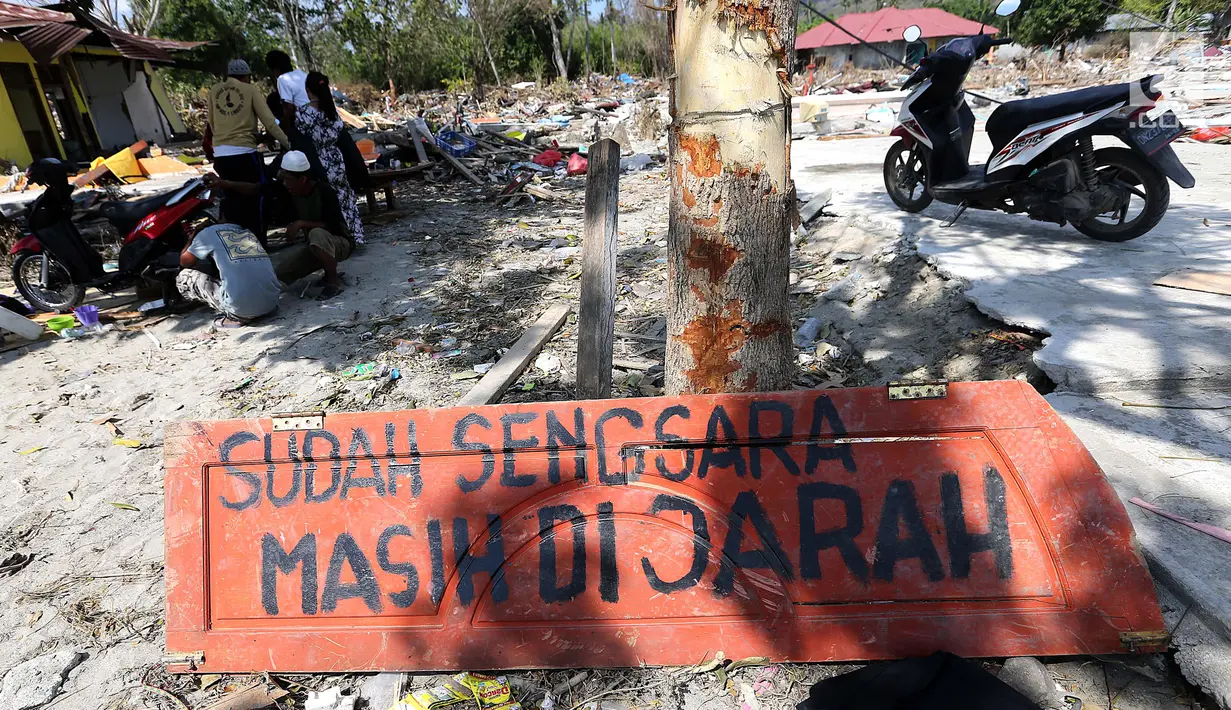 Sebuah papan dengan pesan Sudah Sengsara Masih Dijarah dipasang pasca gempa bumi dan tsunami di pinggir Jalan Trans Sulawesi, Palu, Sulawesi Tengah, Kamis (4/10). (Liputan6.com/Fery Pradolo)