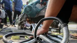 Petugas tampak memotong selang karet elpiji yang sengaja dimusnahkan karena tidak sesuai dengan SNI di Lapangan Parkir Gedung Kementerian Perdagangan, Jakarta, Jumat (22/5/2015). (Liputan6.com/Faizal Fanani)