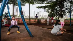Sejumlah anak bermain di taman bermain yang terdapat di Bantaran Banjir Kanal Barat Kawasan Petamburan, Jakarta, Minggu (12/12/2021). Taman di bantaran kali kawasan padat penduduk itu menjadi sarana bermain bagi anak-anak di sekitarnya. (Liputan6.com/Faizal Fanani)