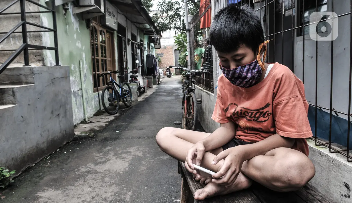 Seorang anak mengenakan masker saat bermain di depan rumah di RW 004, Cipinang Melayu, Jakarta, Rabu (27/1/2021). Pemprov DKI Jakarta mencatat sebanyak 54 rukun warga (RW) menjadi zona merah Covid-19 per 21 Januari 2021. (merdeka.com/Iqbal S Nugroho)