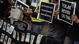 Aktivis Jaringan Solidaritas Korban untuk Keadilan (JSKK) membawa foto para korban masalah HAM masa lalu saat menggelar aksi Kamisan ke-575 di depan Istana Merdeka, Jakarta, Kamis (21/2). (Liputan6.com/FaizalFanani)