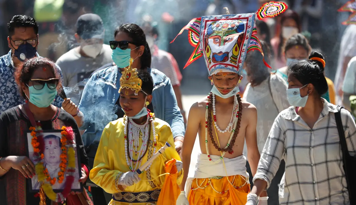 Anggota komunitas Newar mengenakan kostum dan masker saat berpartisipasi dalam prosesi 'Gai Jatra', atau festival sapi, di Kathmandu, Nepal, Selasa (4/8/2020). Sapi dianggap sebagai hewan suci bagi pemeluk Hindu yang membantu jiwa-jiwa yang telah pergi mencapai surga. (AP Photo/Niranjan Shrestha)