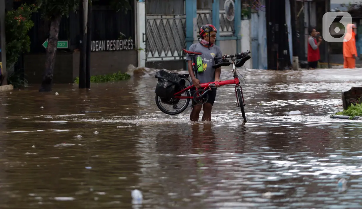 Warga mengangkat sepedanya saat melewati banjir yang menggenangi kawasan Jalan Wolter Monginsidi Jakarta dan sekitarnya, Sabtu (20/2/2021). Hujan yang mengguyur Jakarta sejak Jumat (19/2) membuat sejumlah titik di Jakarta terendam banjir. (Liputan6.com/Helmi Fithriansyah)