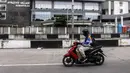 Pengendara sepeda motor melintas dekat tempat karantina pasien COVID-19 Wisma Atlet, Jakarta, Kamis (3/3/2022). Hingga dua tahun berselang, pada 2 Maret 2022, pemerintah mencatat ada 5.630.096 kasus positif COVID-19 di Indonesia sejak pengumuman kasus pertama. (Liputan6.com/Johan Tallo)