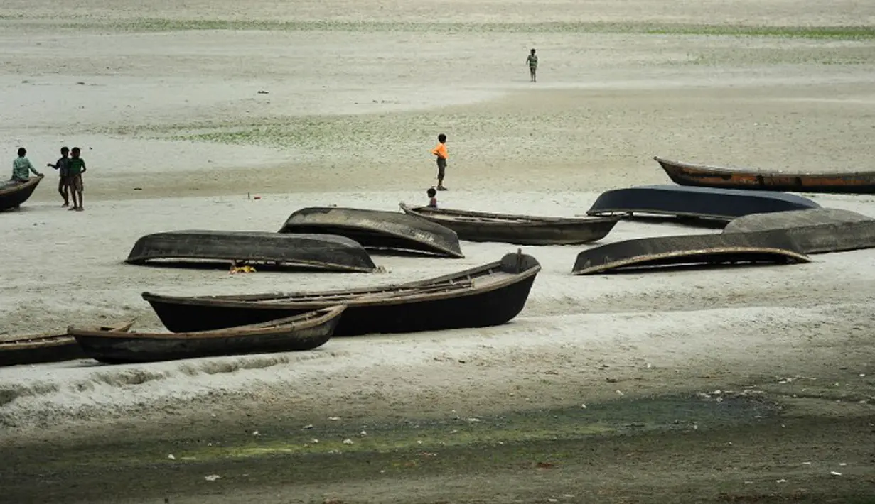 Anak-anak bermain di dekat perahu nelayan di sebuah sungai kering di Allahabad, India (3/6/2015). Cuaca panas yang melanda India tidak hanya menewaskan ratusan warga, tetapi mengubah sungai menjadi seperti lapangan.  (AFP PHOTO/SANJAY Kanojia) 