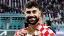 Bek Kroasia, Josko Gvardiol, tersenyum saat menunjukkan medali Piala Dunia 2022 Qatar. (AFP/Jack Guez)