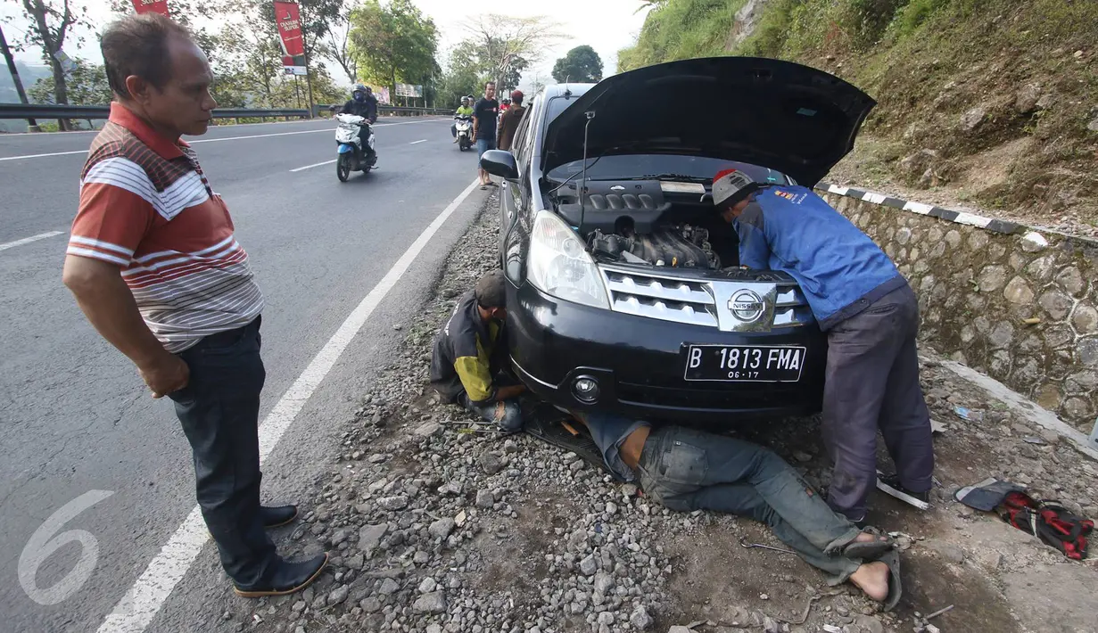 Pemilik mobil memperhatikan mobilnya yang tengah diperbaiki oleh montir di Jalan Warung Peuteuy, Garut, Jabar, Senin (4/7). Banyaknya kendaraan pemudik yang rusak menjadi berkah bagi para montir panggilan. (Liputan6.com/Immanuel Antonius)