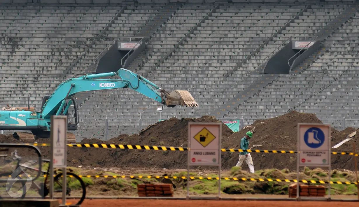 Pekerja melintas di lapangan bola Stadion GBK Jakarta saat proses renovasi, Selasa (18/10). Pengerjaan renovasi Stadion GBK bagian persiapan jelang Asian Games 2018 dan ditargetkan selesai Oktober 2017. (Liputan6.com/Helmi Fithriansyah)