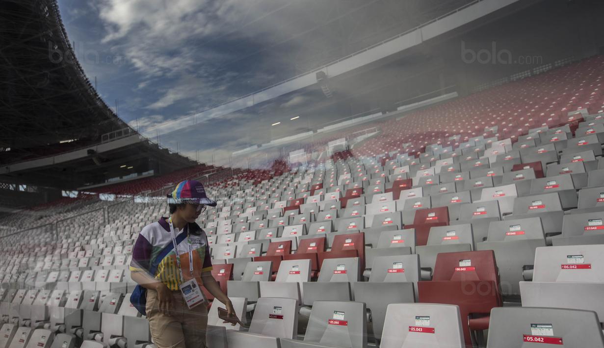 Seorang tenaga relawan melintasi deretan kursi di Stadion Utama Gelora Bung Karno, Jakarta, Jumat (9/8/2018). Lokasi ini akan dijadikan venue dari invitation tournament cabang atletik. (Bola.com/Vitalis Yogi Trisna)