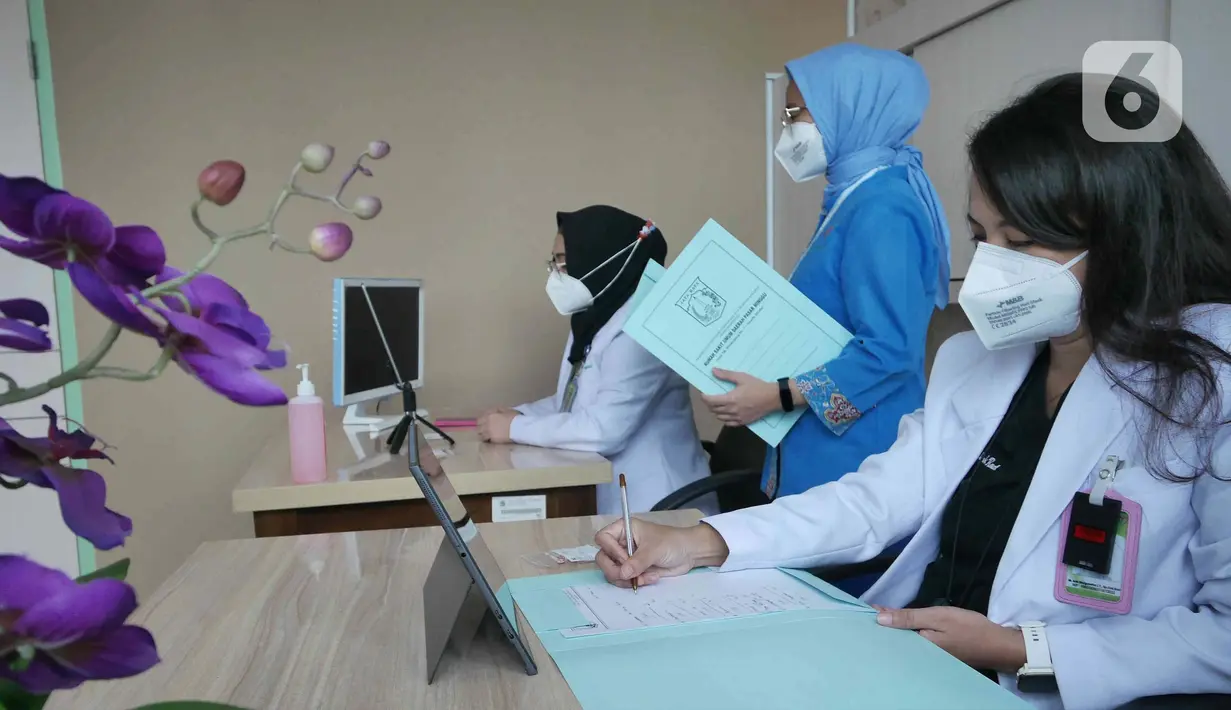 Dokter Spesialis Onkologi Radiasi, Ade Margaretha (kanan) bersama Dokter Umum Indria Febriani (kiri) saat memberikan pelayanan medis jarak jauh atau Telemedicine pada pasien umum di Rumah Sakit Umum Daerah (RSUD) Pasar Minggu, Jakarta, Jumat (18/2/2022). (Liputan6.com/Herman Zakharia)