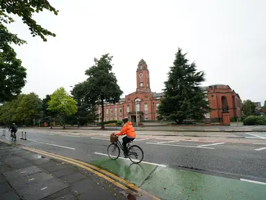 Seorang pesepeda melintas di Trafford Town Hall, Greater Manchester, Inggris (2/9/2020). Menurut BBC, sejumlah wilayah di Greater Manchester tidak akan melonggarkan pembatasan lockdown sesuai rencana awal karena pemerintah membatalkannya. (Xinhua/Jon Super)