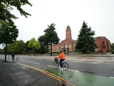 Seorang pesepeda melintas di Trafford Town Hall, Greater Manchester, Inggris (2/9/2020). Menurut BBC, sejumlah wilayah di Greater Manchester tidak akan melonggarkan pembatasan lockdown sesuai rencana awal karena pemerintah membatalkannya. (Xinhua/Jon Super)