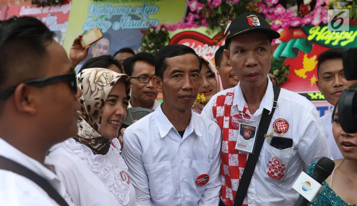 Seorang pria berwajah mirip Presiden Joko Widodo (Jokowi) berswafoto bersama warga yang memadati sekitar Gedung Graha Saba Buana, Solo, Rabu (8/11). Pria bernama David itu beberapa saat berhasil mengecoh warga. (Liputan6.com/Angga Yuniar)
