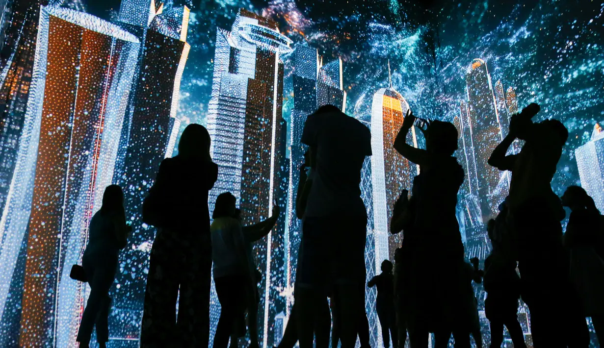 Pengunjung mengambil gambar saat pertunjukan cahaya dalam pameran untuk mempromosikan Piala Dunia 2022 di museum multimedia Qatar Elements, Gorky Park, Moskow, Rusia, Kamis (12/7). (Maxim ZMEYEV/AFP)