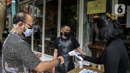 Warga diukur suhu tubuh sebelum menerima kopi gratis di Filosofi Kopi Melawai, Jakarta, Rabu (30/6/2021). Filosofi Kopi memberikan kopi gratis bagi warga yang telah melakukan vaksinasi COVID-19.. (Liputan6.com/Faizal Fanani)