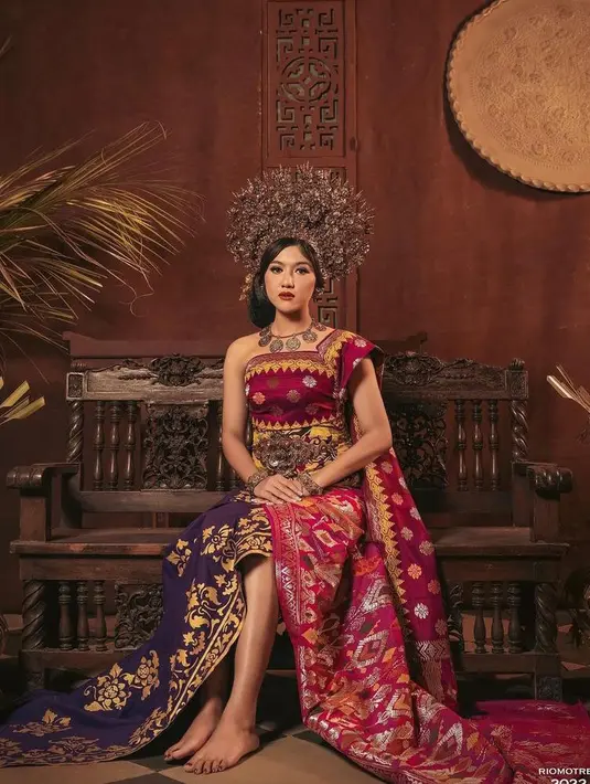 Erina Gudono mengenakan kain adat Bali yang dililit dengan selendang. Rambutnya disanggul khas Bali, serta dihiasi aksesori kepala berupa mahkota yang megah. @kaesangp.