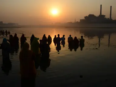 Umat Hindu India mengambil bagian dalam ritual pemujaan dewa matahari selama Festival Chhath Puja di tepi sungai Sabarmati, Ahmedabad, Selasa (13/11). Festival Hindu kuno ini dilakukan sebagai bentuk terima kasih kepada Dewa Matahari (SAM PANTHAKY/AF/AFP)