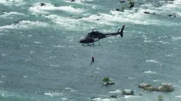 Erendira Wallenda melakukan aksi akrobatik di atas air terjun Niagara, New York, Kamis (15/6). Erendira ditambatkan ke lingkaran besi yang dikaitkan pada helikopter yang terbang 91 meter di atas permukaan air. (Nathan Denette/The Canadian Press via AP)