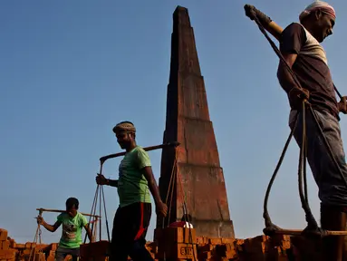 Para pekerja India membawa batu bata di pundak mereka di pabrik pembuatan batu bata di pinggiran Gauhati, India (22/11). Mereka menghasilkan 120 Rupee (kurang dari 2 Dolar) per hari. (AP Photo/Anupam Nath)