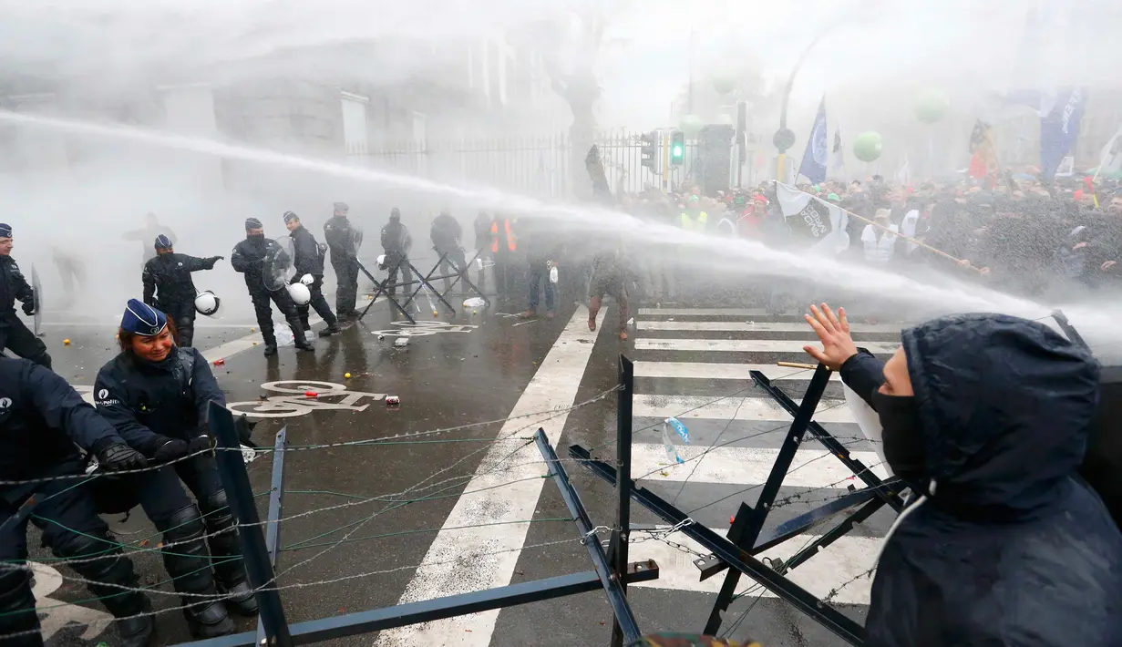 Polisi menyemprotkan air ke arah demonstran saat aksi menolak Reformasi Pensiun di Brussels, Belgia, Selasa (15/11). Mereka menolak rencana pemerintah yang akan menaikkan usia pensiun dari 56 menjadi 63 tahun. (REUTERS / Yves Herman)