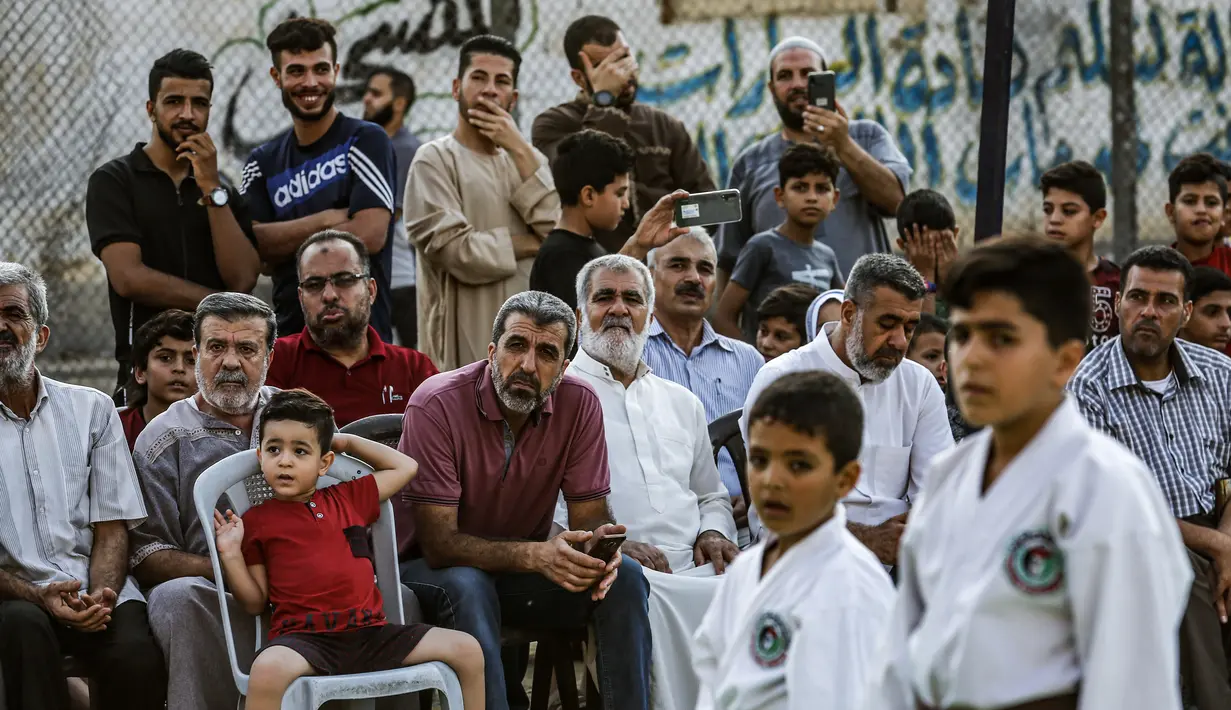 Anggota keluarga menyaksikan anak-anaknya berlatih karate selama upacara promosi Karate di pusat olahraga di kamp Rafah untuk para pengungsi Palestina di Jalur Gaza selatan (20/9/2019). (AFP Photo/Said Khatib)