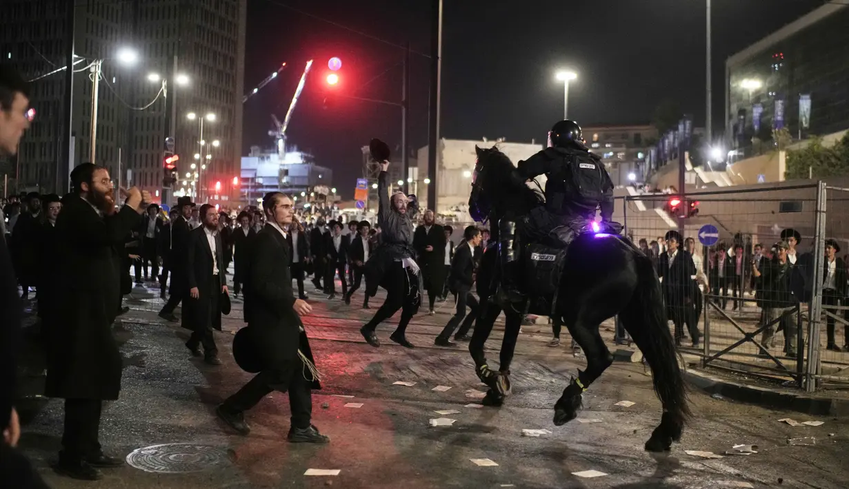 Petugas polisi Israel membubarkan pria Yahudi ultra-Ortodoks yang menghalangi jalan dalam aksi protes menentang rencana wajib militer mereka di Israel, di Yerusalem, Kamis 30 Oktober 2025. Komunitas Yahudi Ortodoks menolak langkah pemerintah yang mewajibkan mereka untuk menjalani wajib militer. (AP Photo/Leo Correa)