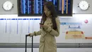 Miss World Kanada Anastasia Lin memainkan ponselnya di Bandara Hong Kong, Kamis (26/11). Lin ditolak menaiki pesawat untuk ikut perlombaan kecantikan di Sanya, China diduga karena dia terlalu vokal menyinggung kasus HAM di negeri itu. (REUTERS/Tyrone Siu)
