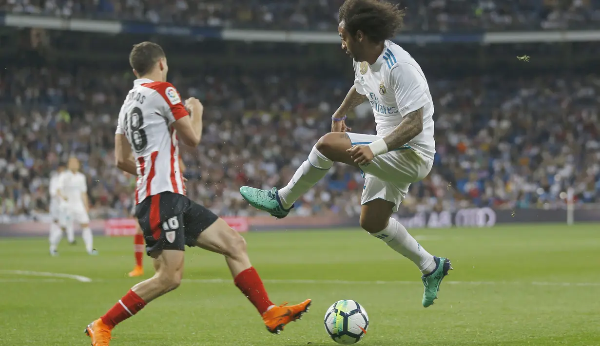 Pemain Real Madrid, Marcelo (kanan) menghalau bola dari kejaran pemain Athletic Bilbao, Oscar de Marcos pada lanjutan La Liga Santander di Santiago Bernabeu stadium, Madrid, (18/4/2018). Real Madrid bermain imbang 1-1 dengan Bilbao. (AP/Francisco Seco)