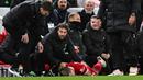 Pemain Liverpool, Kostas Tsimikas, terkapar setelah berduel dengan pemain Arsenal, Bukayo Saka pada laga pekan ke-18 Premier League 2023/2024 di Stadion Anfield, Minggu (24/12/2023). (AFP/Paul Ellis)