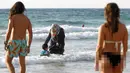 Seorang wanita Muslim bersama anaknya saat berada di pantai di Tel Aviv, Israel pada 22 Agustus 2016. Meski berada di pantai, wanita muslim ini tetap mengenakan jilbab dan busananya. (REUTERS / Baz Ratner)