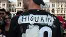 Seorang tifosi AC Milan mengenakan jersey bernama Higuain sebelum kedatangan pemain Argentina tersebut di alun-alun pusat Milan Piazza Duomo (3/8). Higuain akan membela I Rossoneri hingga 30 Juni 2019 dengan status pinjaman. (AFP Photo/Stringer)