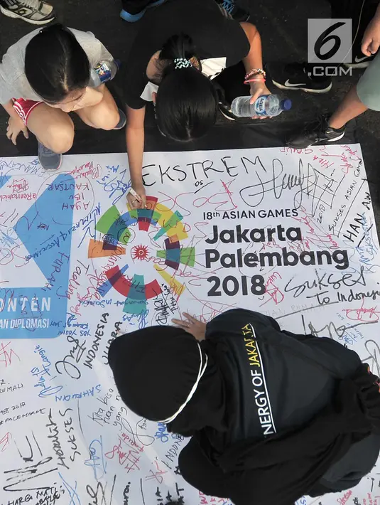 Pengunjung membubuhkan tanda tangan di atas spanduk raksasa saat car free day (CFD) di Bundaran HI, Jakarta, Minggu (22/7). Doa dan pengumpulan tanda tangan ini diinisiasi Komunikonten untuk mendukung atlet Asian Games 2018. (Merdeka.com/Iqbal Nugroho)