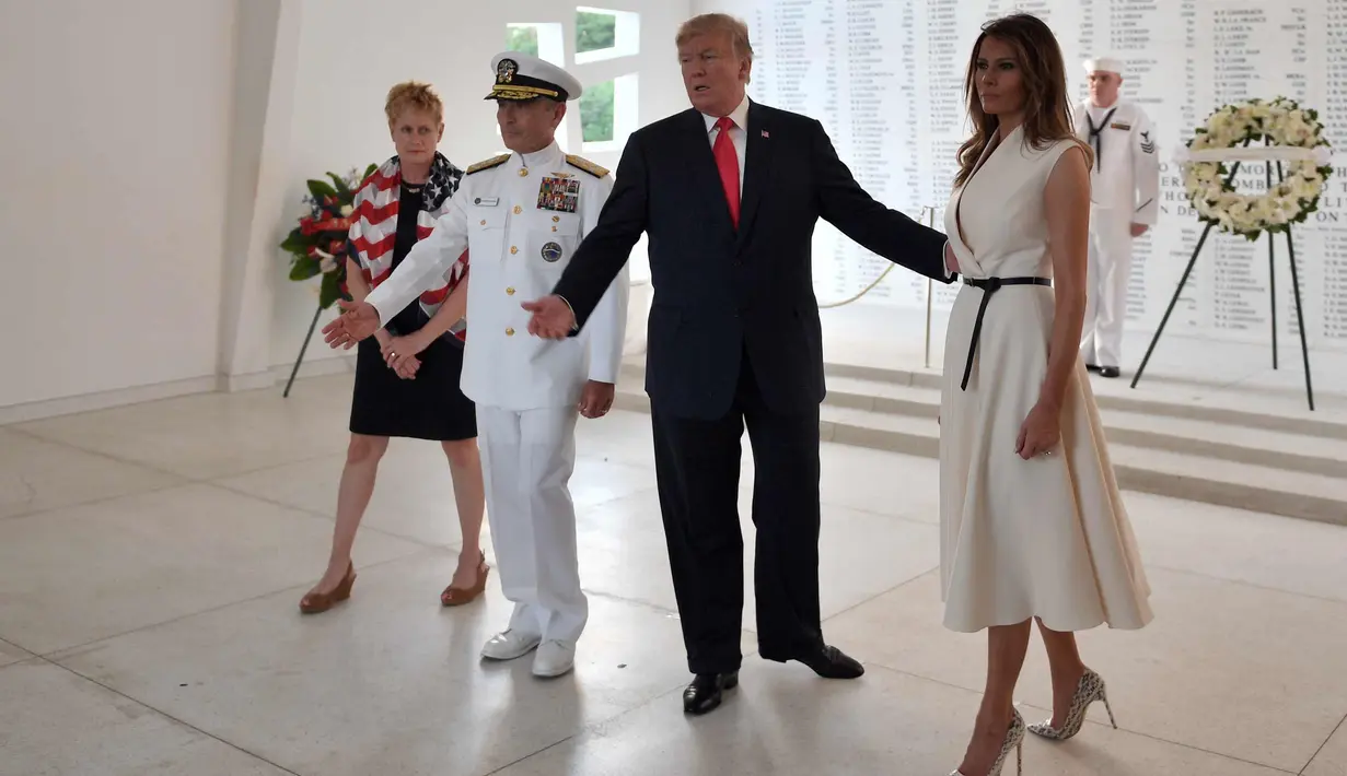 Presiden AS, Donald Trump dan Ibu Negara Melania Trump didampingi Komandan Komando Adm Harry Harris  dan istrinya Bruni Bradley berpartisipasi dalam upacara peletakan karangan bunga di USS Arizona Memorial, Hawaii (3/11). (AFP Photo/Jim Watson)