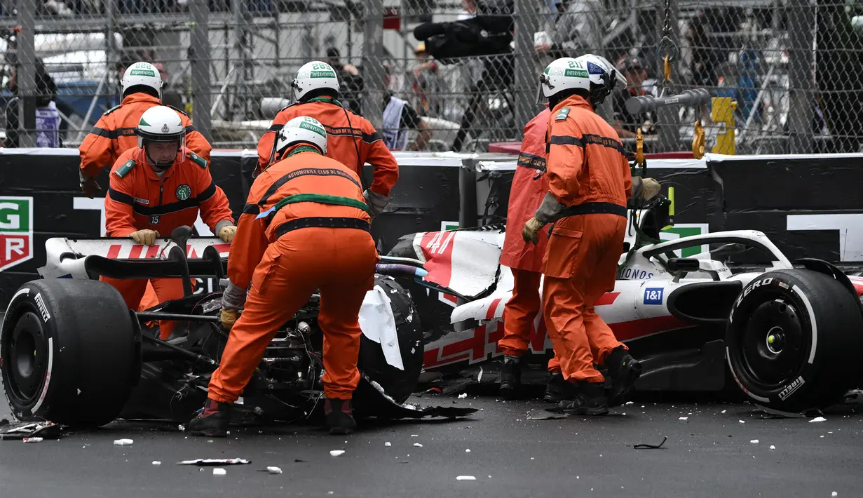 Sejumlah marshall berusaha mengevakuasi mobil pembalap Haas, Mick Schumacher usai mengalami kecelakaan saat Formula 1 GP Monako yang berlangsung di Circuit de Monaco, Minggu, 29 Mei 2022. (AFP/Loic Venance)