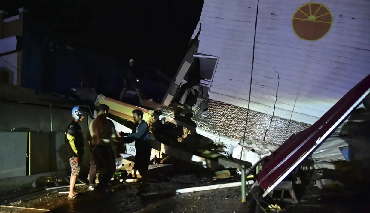 Tim penyelamat mencari korban pada sebuah bangunan yang runtuh usai diguncang gempa, Kota Mamuju, Sulawesi Barat, Indonesia, Jumat (15/1/2021). Gempa dirasakan sejumlah daerah seperti Polman, Mamuju, Mamuju Tengah, Pasangkayu, dan daerah di Sulawesi Selatan. (Firdaus/AFP)